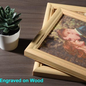 May include: A framed photo of a couple kissing, engraved on a wooden surface. The photo is in a natural wood frame.