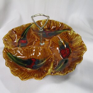 May include: A brown ceramic serving dish with four sections and a metal handle. The dish is decorated with green and red leaves and berries.