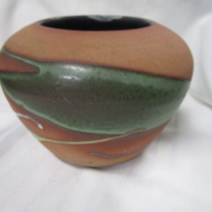 May include: A brown ceramic vase with green, white, and orange glaze. The vase has a rounded shape and a wide opening.