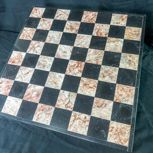 May include: A black and white marble chessboard with a red and white marbled pattern. The board is made of natural stone and has a polished finish.
