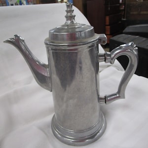May include: A silver metal teapot with a lid and a handle. The teapot has a rounded body and a spout.