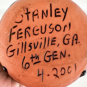 Puede incluir: Un objeto redondo de cer&aacute;mica de color terracota con texto escrito a mano en negro que dice "Stanley Ferguson, Gillisville, GA. 6th Gen. 4-2001".