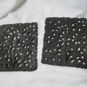 May include: Two dark gray, rectangular bookends with a textured surface and numerous irregular holes. Each bookend is divided into two sections, joined by a metal strip. The bookends are displayed on a white cloth.