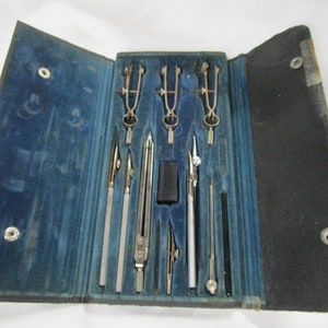 May include: A vintage drafting compass set in a blue velvet lined case. The set includes a variety of compasses, rulers, and other tools.