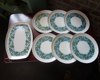 May include: Set of seven white plates with a green and blue paisley pattern. The plates are round and oval shaped.