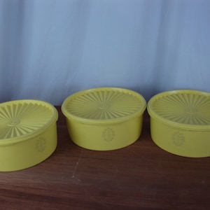 May include: Three yellow plastic storage containers with lids. The containers are round and have a fluted design on the lids.