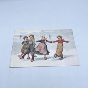 May include: A vintage postcard with a watercolour illustration of four children ice skating. The children are dressed in traditional Dutch clothing, with windmills in the background. The colour palette includes muted tones of brown, red, and blue, set against a snowy landscape.