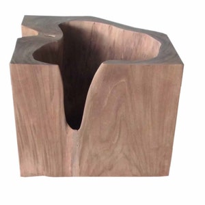 May include: A large, natural wood bowl with a unique, irregular shape. The bowl is made from a single piece of wood and has a natural, rustic finish.