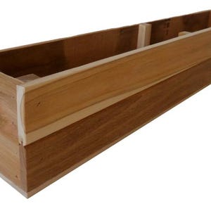 May include: A rectangular wooden planter box with a natural wood finish. The box is constructed from light and dark brown wood, with visible grain. The design features a long, open interior, suitable for plants or other decorative items.