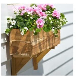 May include: A wooden window box planter filled with vibrant pink and white flowers and green foliage. The rectangular box is mounted on a light-colored wall with wooden brackets. The planter is made of natural wood.