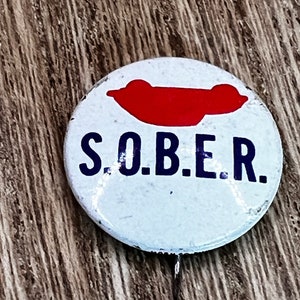 May include: A white button with a red car silhouette and the text "S.O.B.E.R." in blue letters.