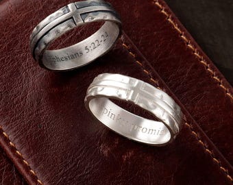May include: Two silver-toned rings with a textured cross design on the exterior. The top ring is engraved with the text Ephesians 5:22-24 on the inner band, while the bottom ring features the engraved text pinky promise on the inner band.