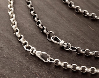 May include: A silver-toned rolo chain necklace featuring round, interlocking links with a polished finish. The chain includes a secure, functional lobster claw clasp mechanism that allows for easy fastening and adjustment of the necklace length.