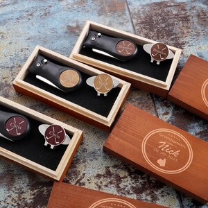 May include: Four wooden boxes with engraved text and a golf ball marker and knife set inside each box. The boxes are labeled "Groomisman Nick 06.09.2025", "Groomisman Brandon 06.09.2025", "Chris", and "Chris".