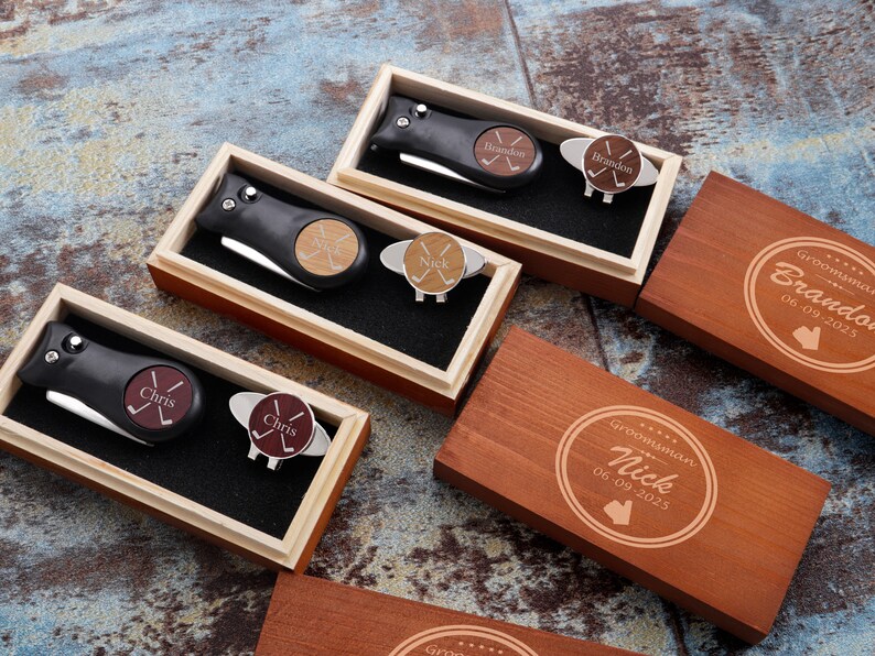 May include: Four wooden boxes with engraved text and a golf ball marker and knife set inside each box. The boxes are labeled "Groomisman Nick 06.09.2025", "Groomisman Brandon 06.09.2025", "Chris", and "Chris".