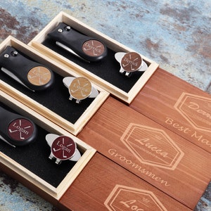 May include: Four wooden boxes with engraved names and the words "Best Man" and "Groomsmen". Each box contains a black golf tool with a wooden engraved disc and a golf ball marker.