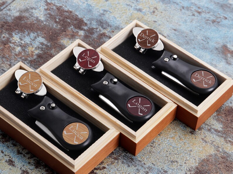 May include: Four wooden boxes each containing a golf ball marker and a golf tool with a personalized name on each. The names are Derrick, Logan, and Lucca.