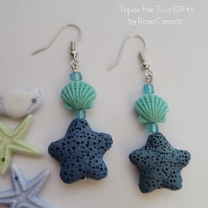 May include: A pair of blue and turquoise earrings with a starfish charm and a seashell charm. The earrings are made with lava rock and glass beads.  Tapas for Two Gifts by Rosa Casado.