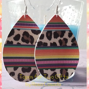 May include: A pair of teardrop-shaped earrings with a colorful striped pattern and a leopard print design. The earrings are made of leather and have silver hooks.
