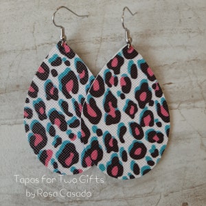 May include: A pair of teardrop-shaped earrings with a white, black, pink, and blue leopard print pattern. The earrings are made of faux leather and have silver hooks.