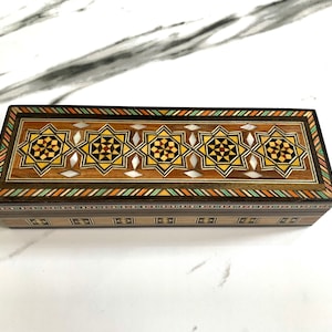 May include: A rectangular wooden box with intricate inlaid geometric patterns in shades of brown, beige, and white. The box has a hinged lid and is decorated with a border of alternating colors.