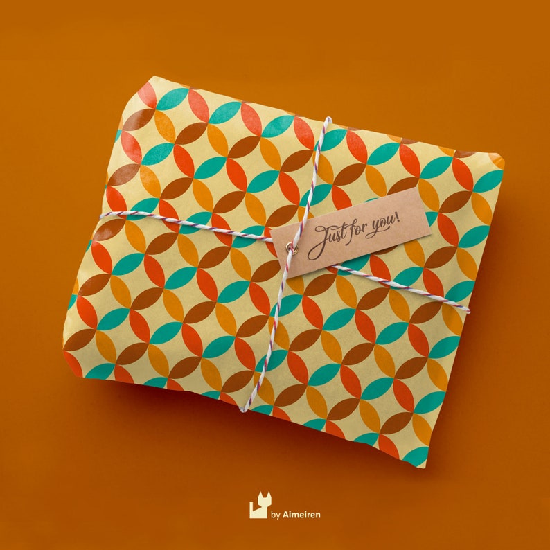 Op de afbeelding: Een cadeau verpakt in bruin papier met een geometrisch patroon van oranje, turquoise en bruine cirkels. Het papier is vastgebonden met wit touw en een bruin label met de tekst "Just for you!"