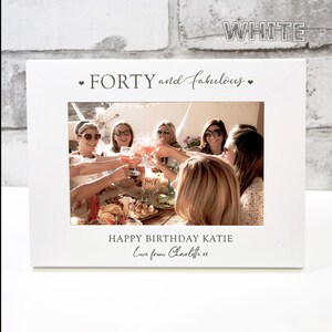 Op de afbeelding: Wit fotolijstje met de tekst "FORTY and fabulous" en een foto van een groep vrienden die feest vieren. De tekst "HAPPY BIRTHDAY KATIE Love from Charlotte xx" is ook inbegrepen.
