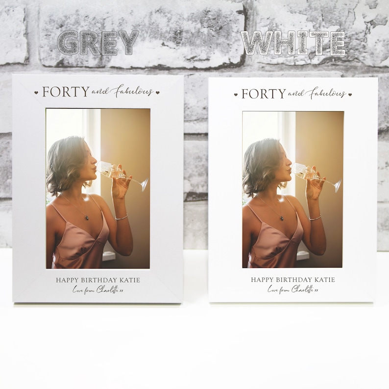 Op de afbeelding: Twee witte fotolijsten met een foto van een vrouw die champagne drinkt. De tekst op de lijsten luidt "FORTY and fabulous." en "HAPPY BIRTHDAY KATIE Love from Charlotte".