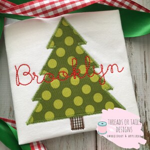 May include: A white t-shirt with a green and yellow polka dot Christmas tree applique and the name "Brooklyn" embroidered in red thread.
