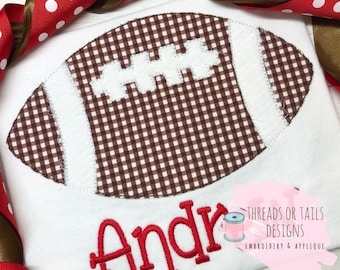 May include: White fabric with a brown and white gingham football applique and the name "Andre" embroidered in red.