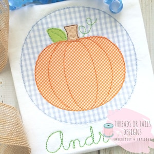 May include: A white onesie with a blue and white gingham circle containing an orange pumpkin with a green stem and leaves. The name "Andri" is embroidered in green below the pumpkin. The text "Threads or Tails Designs Embroidery & Applique" is in the bottom right corner.