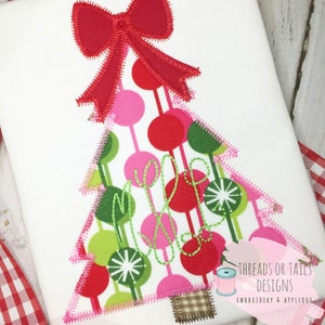 May include: Embroidered Christmas tree design with a red bow, green and pink circles, and the text "Merry" in cursive. The design is on a white fabric background.