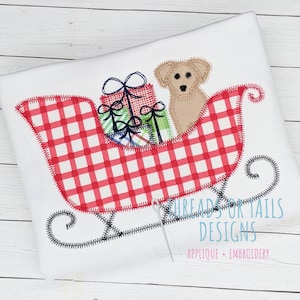 May include: A red and white checkered sled with a brown dog and wrapped presents. The sled has a black outline and a black handle. The text "Threads for Tails Designs Applique + Embroidery" is at the bottom of the image.