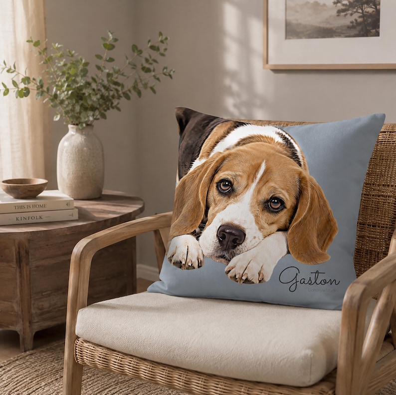 May include: A square throw pillow with a light blue background featuring a realistic portrait of a beagle dog resting its head on its front paws. The name Gaston is printed in a dark cursive script in the bottom right corner of the pillow.