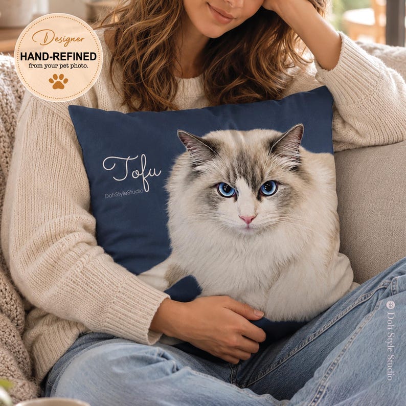 May include: A square navy blue throw pillow featuring a printed portrait of a long-haired white and grey cat with bright blue eyes. The name Tofu is written in white cursive script on the left side, with the text DohStyleStudio printed below.