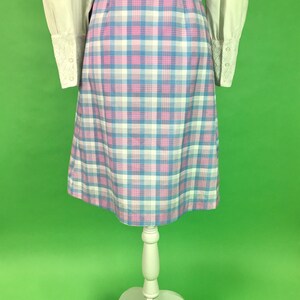 Op de afbeelding: Een geruite rok in tinten roze, blauw en wit. De rok is knielengte en heeft een aansluitende taille.