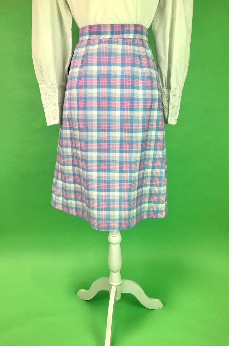 Op de afbeelding: Een geruite rok in tinten roze, blauw en wit. De rok is knielengte en heeft een aansluitende taille.