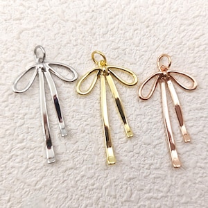 Puede incluir: Tres abalorios de lazo de metal en plata, oro y oro rosa. Cada abalorio presenta un lazo doble con un bucle en la parte superior para sujetarlo a joyas u otras manualidades.