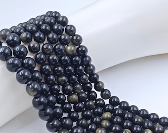 May include: A strand of black and gold beads. The beads are round and have a smooth, polished finish. The beads are strung on a clear thread.