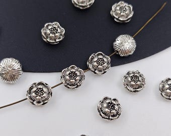 May include: Silver metal flower-shaped beads with a textured surface. The beads are strung on a wire and are perfect for jewelry making or crafting.
