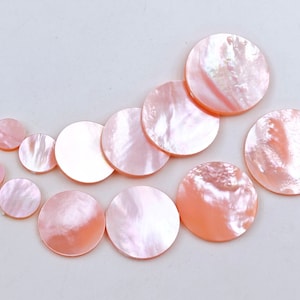 Puede incluir: Surtido de círculos de nácar rosa de diferentes tamaños. Los círculos son lisos y tienen un brillo nacarado.