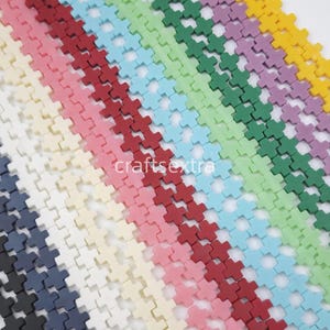 May include: Multiple rows of small, cross-shaped beads arranged in a diagonal pattern. The beads are available in a variety of solid colors including black, navy, white, pink, red, light blue, light green, dark green, purple, and yellow.