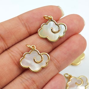 Op de afbeelding: Wolk-vormige bedelhangers met een goudkleurige rand en een parelmoer, wervelend wolkenontwerp. Deze kleine bedels hebben een lus aan de bovenkant voor eenvoudige bevestiging aan sieraden. Ideaal voor doe-het-zelf sieradenprojecten.