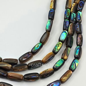 May include: A strand of cylindrical beads made from abalone shell, featuring a dark brown base color with iridescent flashes of green, blue, and purple. The beads are arranged in multiple rows, displaying a smooth, polished finish throughout.