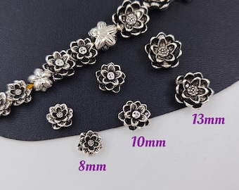 May include: Silver flower-shaped metal beads in three sizes: 8 mm, 10 mm, and 13 mm. The beads have a detailed design and are perfect for jewelry making or crafting.