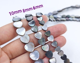 May include: Three strands of heart-shaped shell beads in black and white. The beads are in three sizes: 10mm, 8mm, and 6mm.