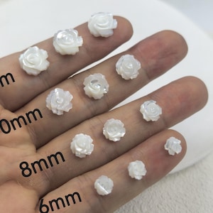 May include: A collection of small, white, rose-shaped beads in various sizes, from 6mm to 12mm, are displayed. The sizes are labeled on the image. These beads are ideal for jewelry making and crafting.