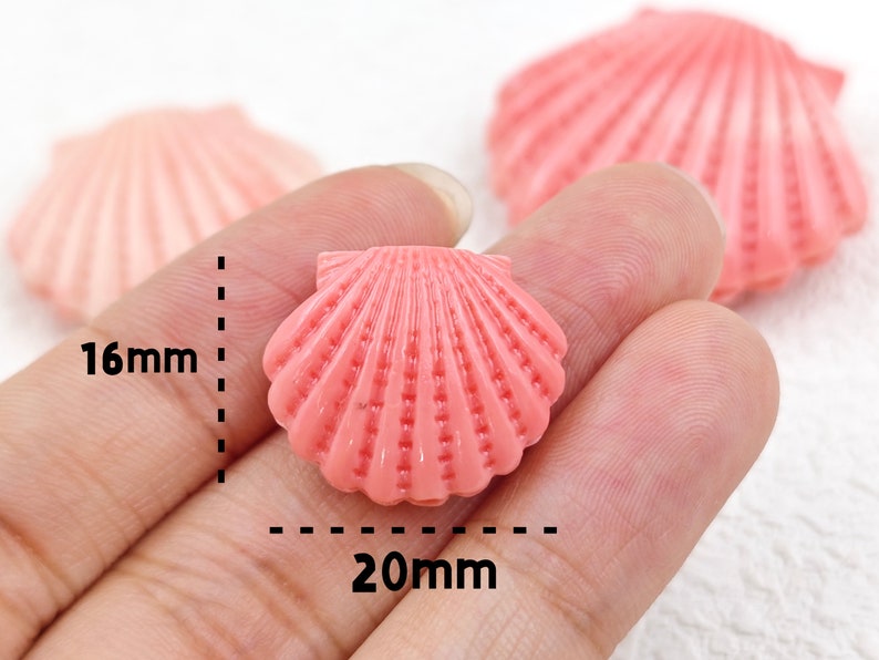 K&ouml;nnte beinhalten: Rosa Plastikperle in Muschelform mit einer L&auml;nge von 20 mm und einer Breite von 16 mm.