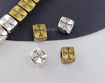 May include: A collection of square-shaped beads featuring a cross emblem on the front. The beads are finished in metallic silver and antique gold tones. The text CRAFTSEXTRA is visible in the centre of the image. These beads have a hole through the centre for stringing.