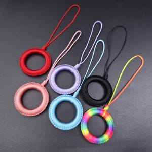 以下が含まれることがあります： 丸い輪が付いたカラフルなカメラストラップ6本。ストラップは編み紐で作られており、赤、ピンク、ラベンダー、黒、青、虹色の6色があります。